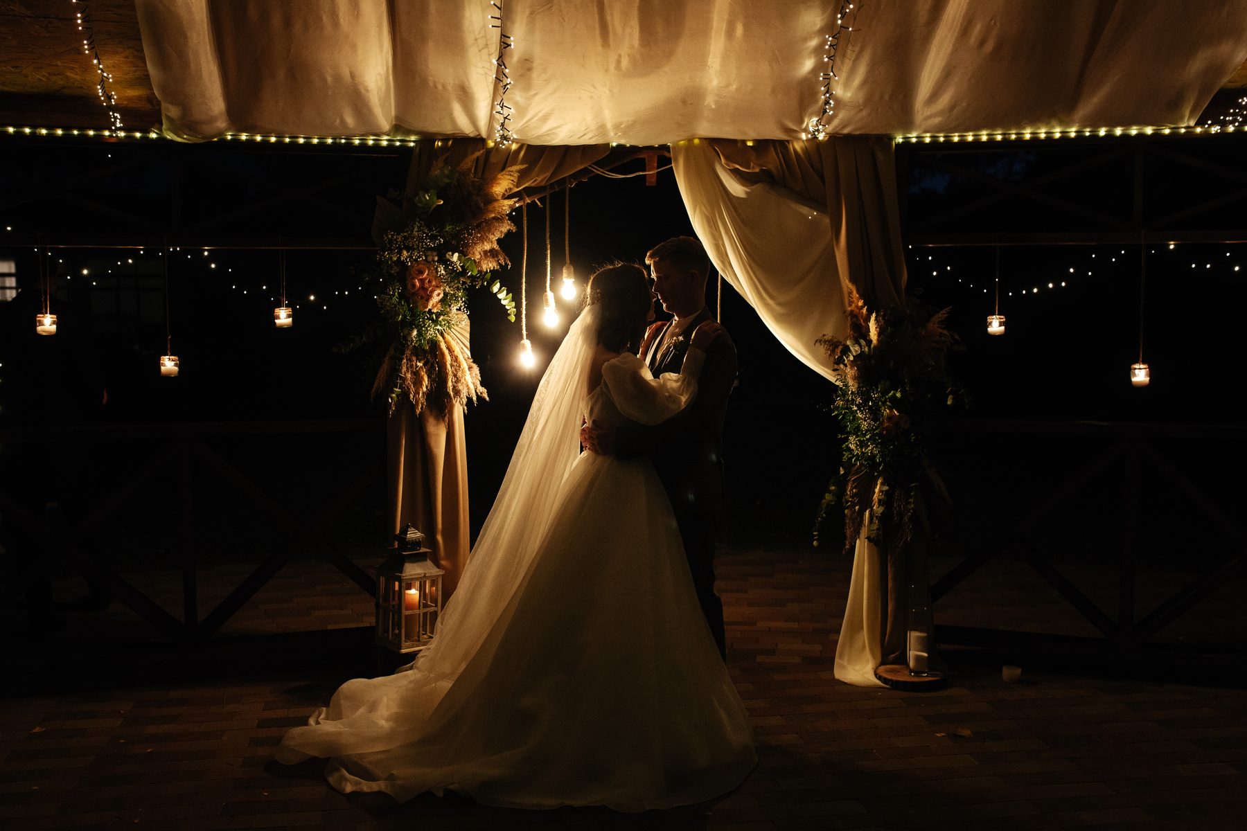 A couple beneath a lit tent canopy in the evening